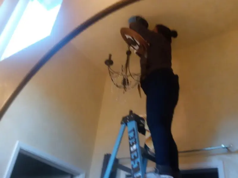 Electrician installing a chandelier in a Derby residence